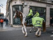 Police officers riding horses through a high street in Cardiff 