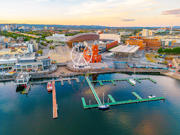 Golygfa o’r awyr o Fae Caerdydd yn dangos y glan dŵr, olwyn fawr, Adeilad y Pierhead coch a cheirios wedi’u hangori yn y marina