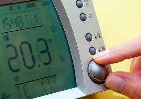 Dyma lun agos o fysedd yn addasu thermostat domestig i dymheredd uchel.