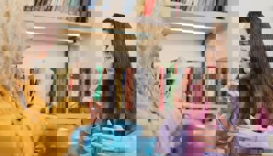 Dwy fenyw yn eistedd wrth fwrdd gyda phot o de, yn cael sgwrs drwy ddefnyddio Iaith Arwyddion Prydain.