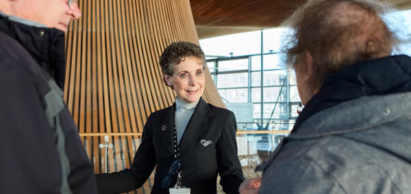 Tywysydd yn tywys pobl ar daith o amgylch y Senedd