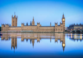 Dau Dŷ Senedd y Deyrnas Unedig yn ystod y dydd o’r ochr draw i Afon Tafwys, a’u hadlewyrchiad yn y dŵr. 