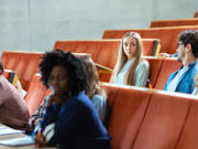 Myfyrwyr yn eistedd mewn darlithfa.