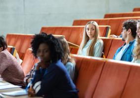 Myfyrwyr yn eistedd mewn darlithfa.