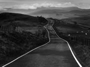 Llun yn dangos creigiau mawr danheddog ar lan y môr. Yn y pellter, gellir gweld amlinelliad bras o’r môr. Mae'r awyr lwyd, dywyll yn llawn cymylau.