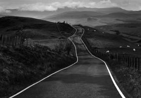 Llun yn dangos creigiau mawr danheddog ar lan y môr. Yn y pellter, gellir gweld amlinelliad bras o’r môr. Mae'r awyr lwyd, dywyll yn llawn cymylau.