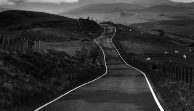 Llun yn dangos creigiau mawr danheddog ar lan y môr. Yn y pellter, gellir gweld amlinelliad bras o’r môr. Mae'r awyr lwyd, dywyll yn llawn cymylau.