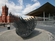 Llun o adeiladau'r Senedd a'r Pierhead, gyda cherflun yn y blaen. 
