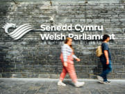 People walking past the Senedd signage