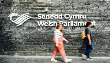 People walking past the Senedd signage