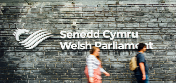 People walking past the Senedd signage