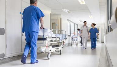 Coridor ysbyty, mae nyrsys yn siarad ac yn gofalu am gleifion